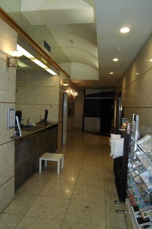 Un'area di accoglienza con un banco reception, un tavolino e un espositore per riviste.
