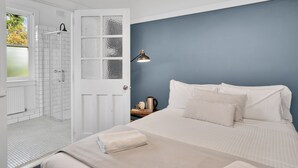 A bedroom with a bed, a nightstand, a lamp, and a view of a white door leading to a bathroom. - Bundanoon Hotel (Bundanoon)