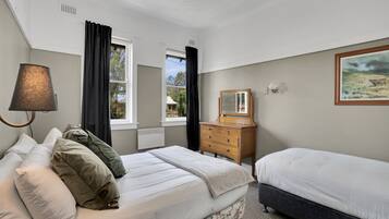 Un dormitorio con cama, cómoda, lámpara, ventana y un cuadro en la pared.