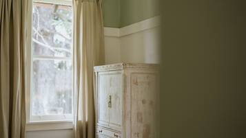 Una stanza con una finestra, un armadietto bianco e tende beige.