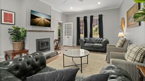 A living room with a fireplace, leather sofas, a coffee table, and a television. - Bundanoon Hotel (Bundanoon)