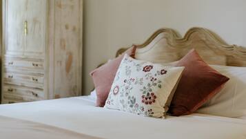 A bed with floral pillows, a wooden headboard, and a white dresser.