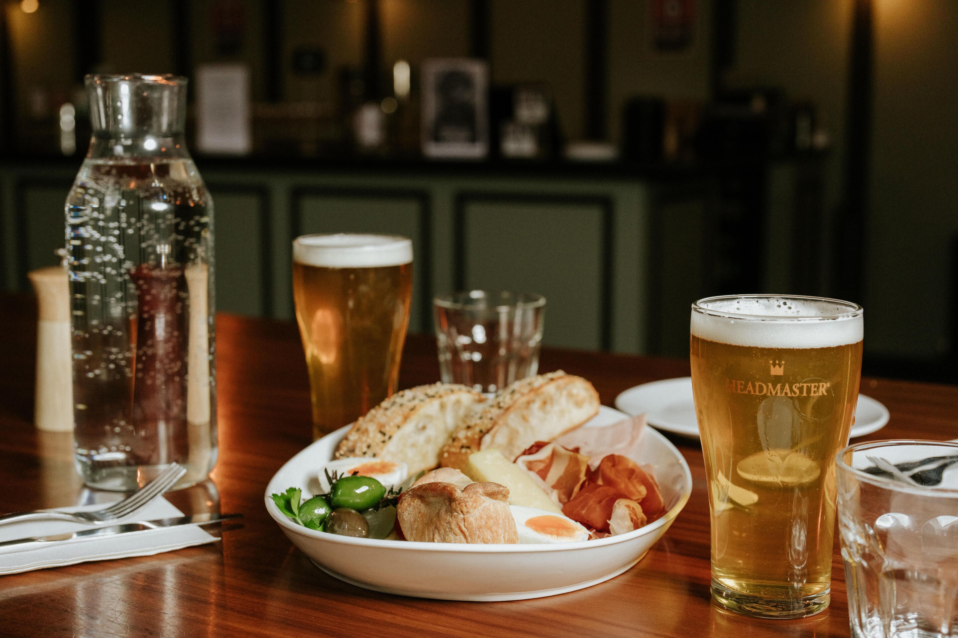 A table with a plate of food, a glass of beer, and a bottle of water.