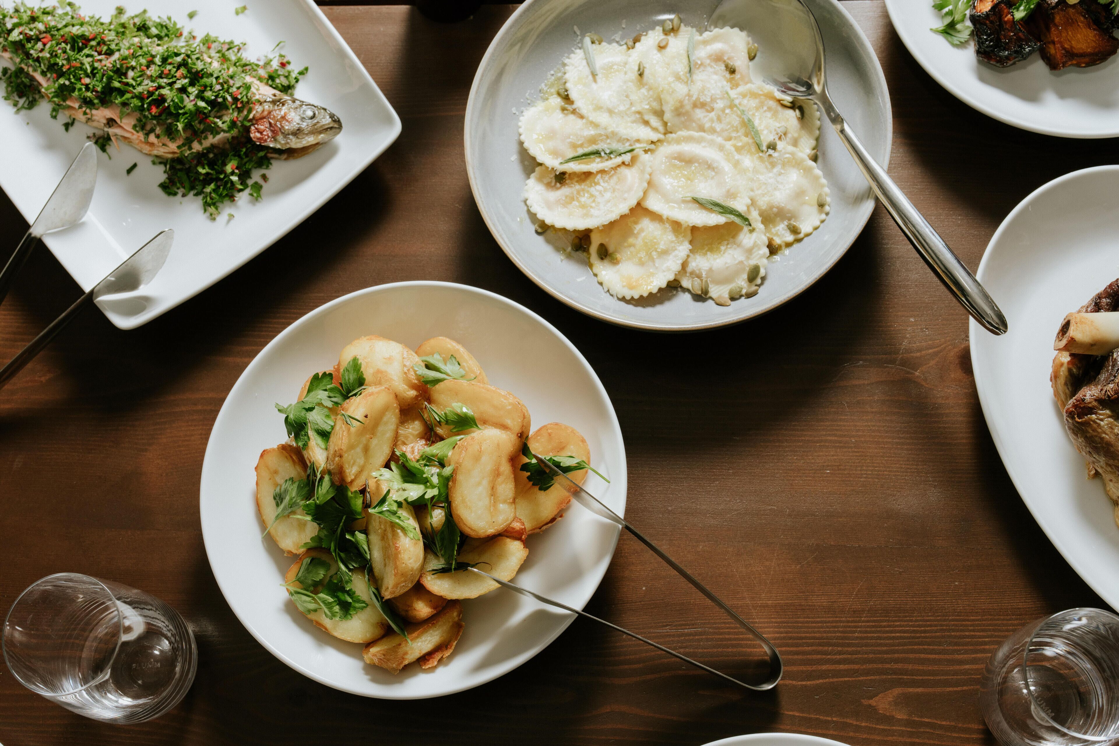 A dining table with various dishes including fish, pasta, and potatoes.