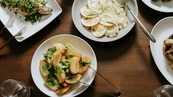 A dining table with various dishes including fish, pasta, and potatoes.
