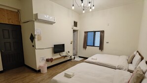 A hotel room with two beds, a TV, an air conditioner, a wooden floor, and a window with curtains. - OC Hostel (Tainan)