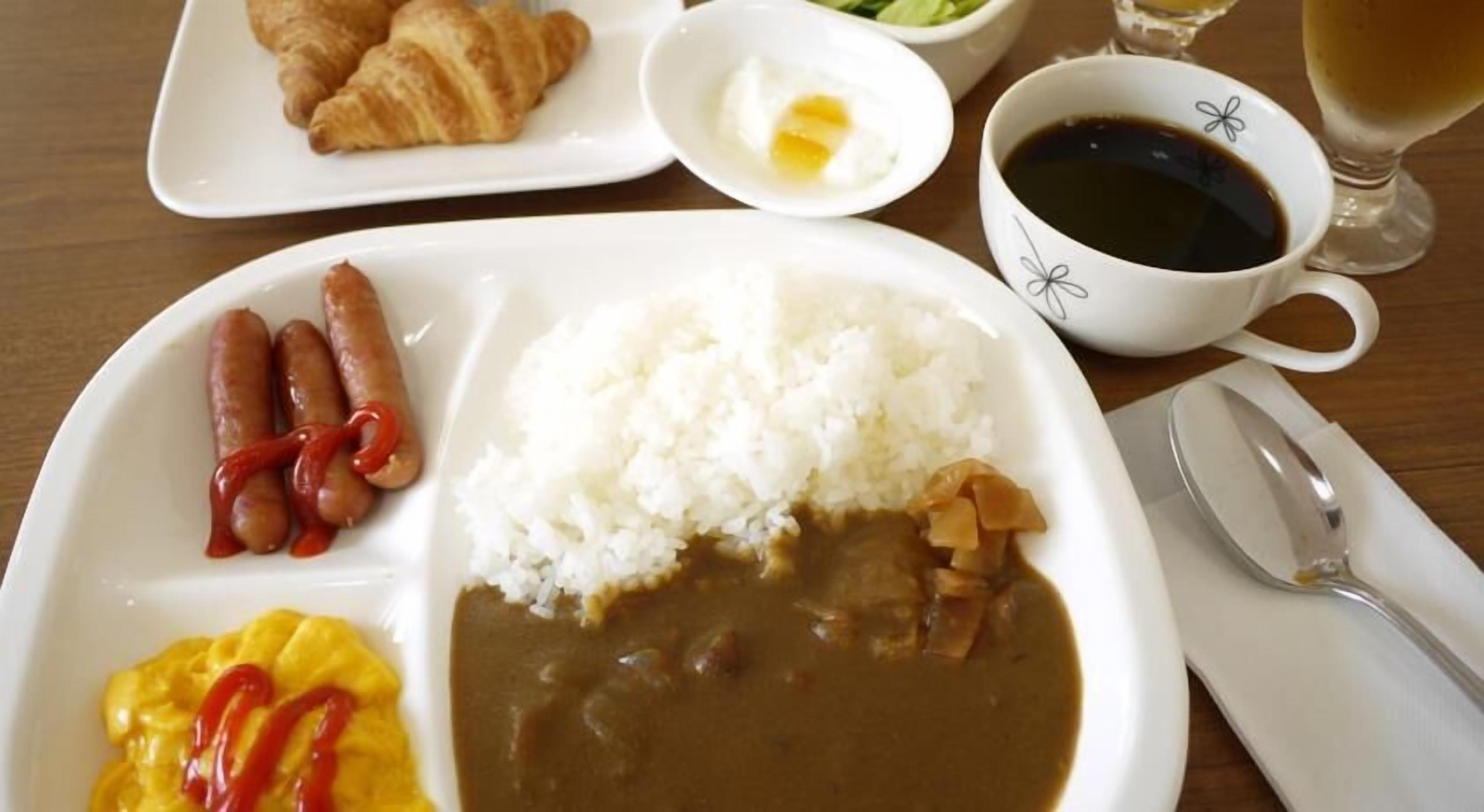 A meal tray with rice, beans, sausages, and a fried egg.