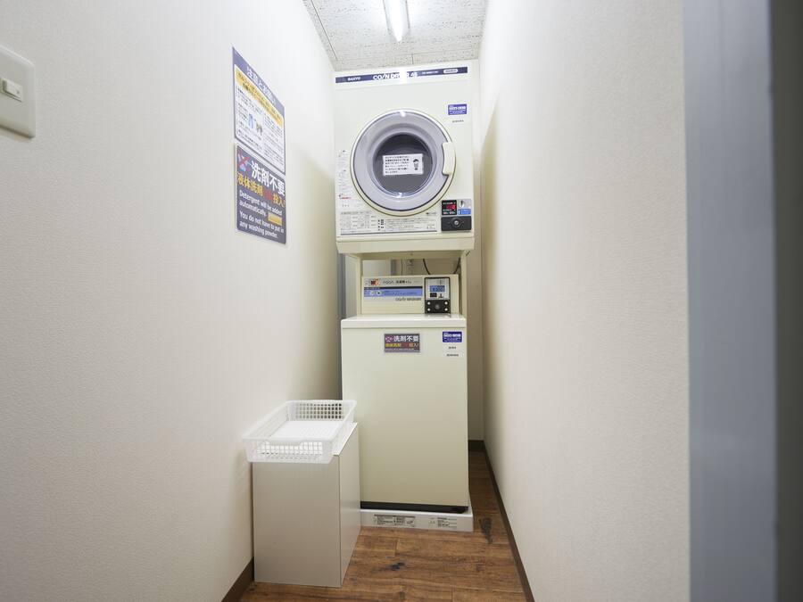 Un cuarto de lavado con lavadora y secadora, un cesto y un cartel con instrucciones.