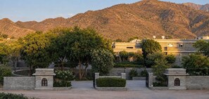 A courtyard with a stone wall, a tree, and a building with multiple windows and a flat roof. - King's Abode (Kumbhalgarh)