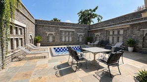 A courtyard with stone walls, a pool, and outdoor seating. - King's Abode (Kumbhalgarh)