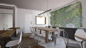 A modern dining area with a wooden table and chairs, a hanging light fixture, and a green vertical garden wall.