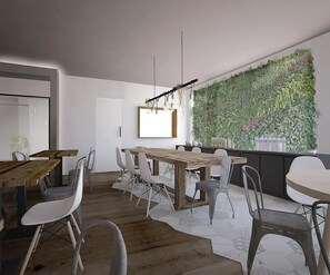 A modern dining area with a wooden table and chairs, a hanging light fixture, and a green vertical garden wall. - Dynamic Hotels Caldetes Barcelona (Arenys de Munt)