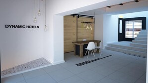 Eine moderne Hotelhalle mit einem Holzbüro, einem weißen Stuhl und einer Treppe, die zu einer oberen Ebene führt.