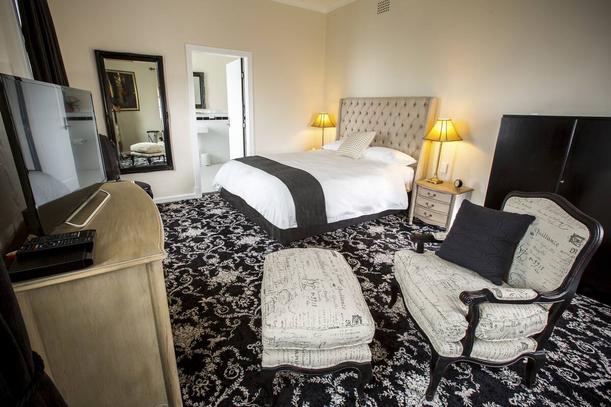 A hotel room with a bed, two bedside tables with lamps, a television, a desk, and a chair.
