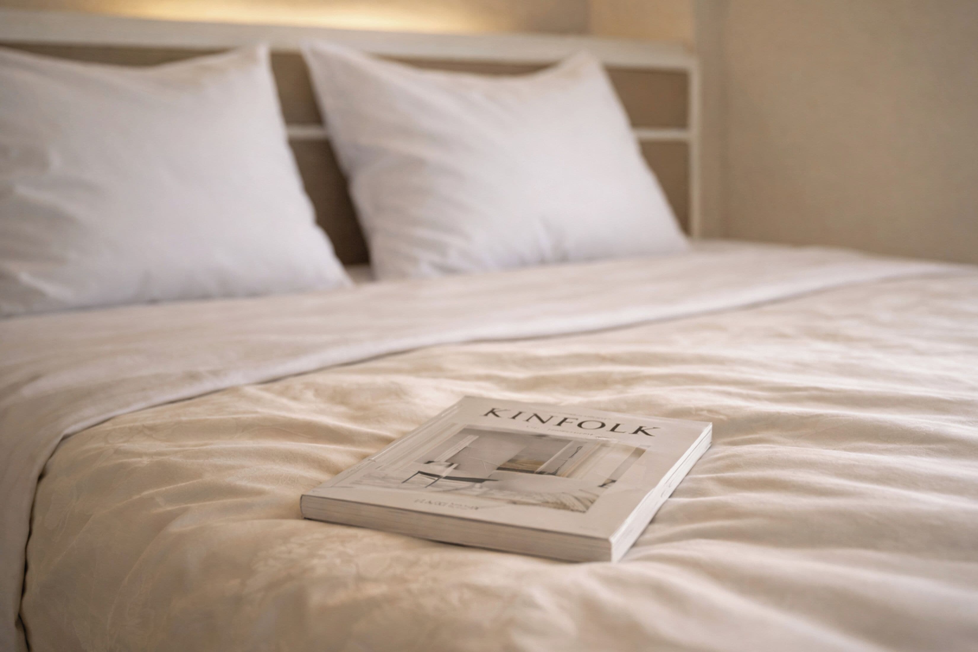 Una cama bien hecha con un libro titulado 'KINFOLK'.