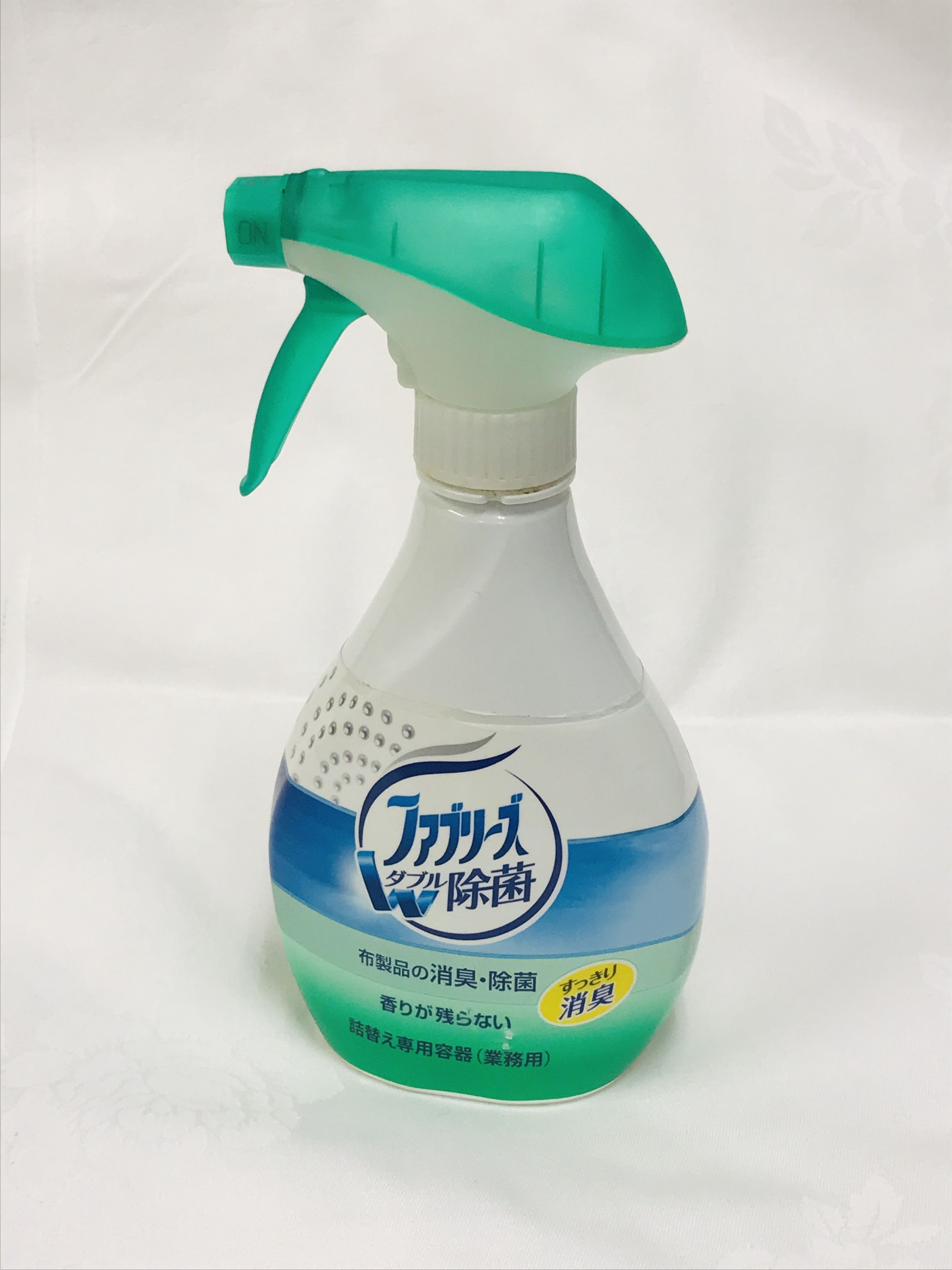 Un atomizador con boquilla verde y una etiqueta con texto en japonés.