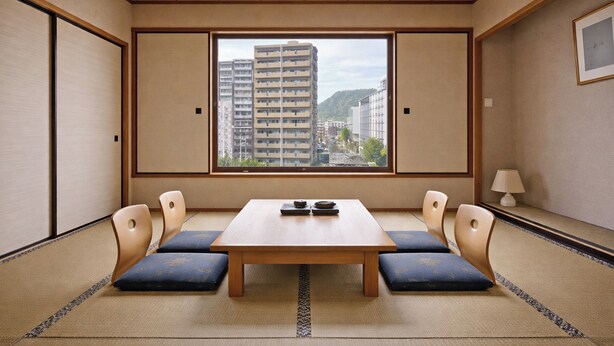 A traditional Japanese room with tatami flooring, a low wooden table, and a view of a cityscape through a large window. - The Celecton Fukushima (Fukushima)