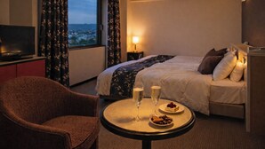 A hotel room with a bed, a round table with two glasses of champagne, a chair, and a TV on a stand. - The Celecton Fukushima (Fukushima)