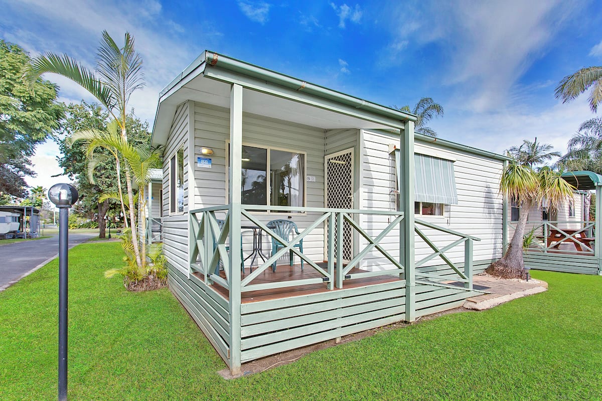 A small, single-story house with a porch and a fenced deck area.