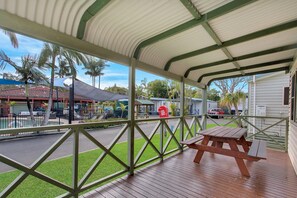 A covered outdoor area with a picnic table and a view of a street with buildings and palm trees. - North Haven Holiday Village (North Haven)