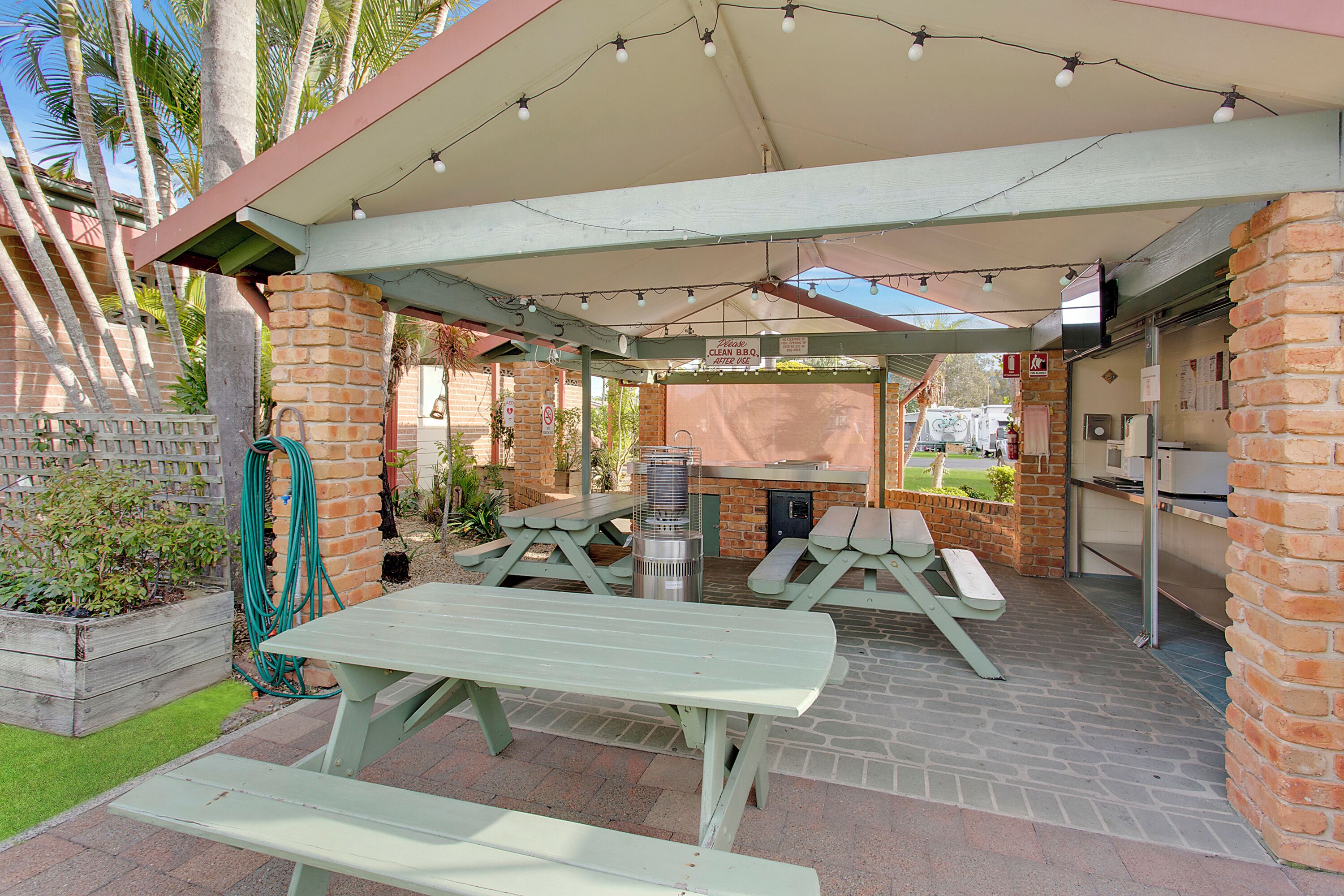 An outdoor patio area with picnic tables, a barbecue grill, and a covered seating area.