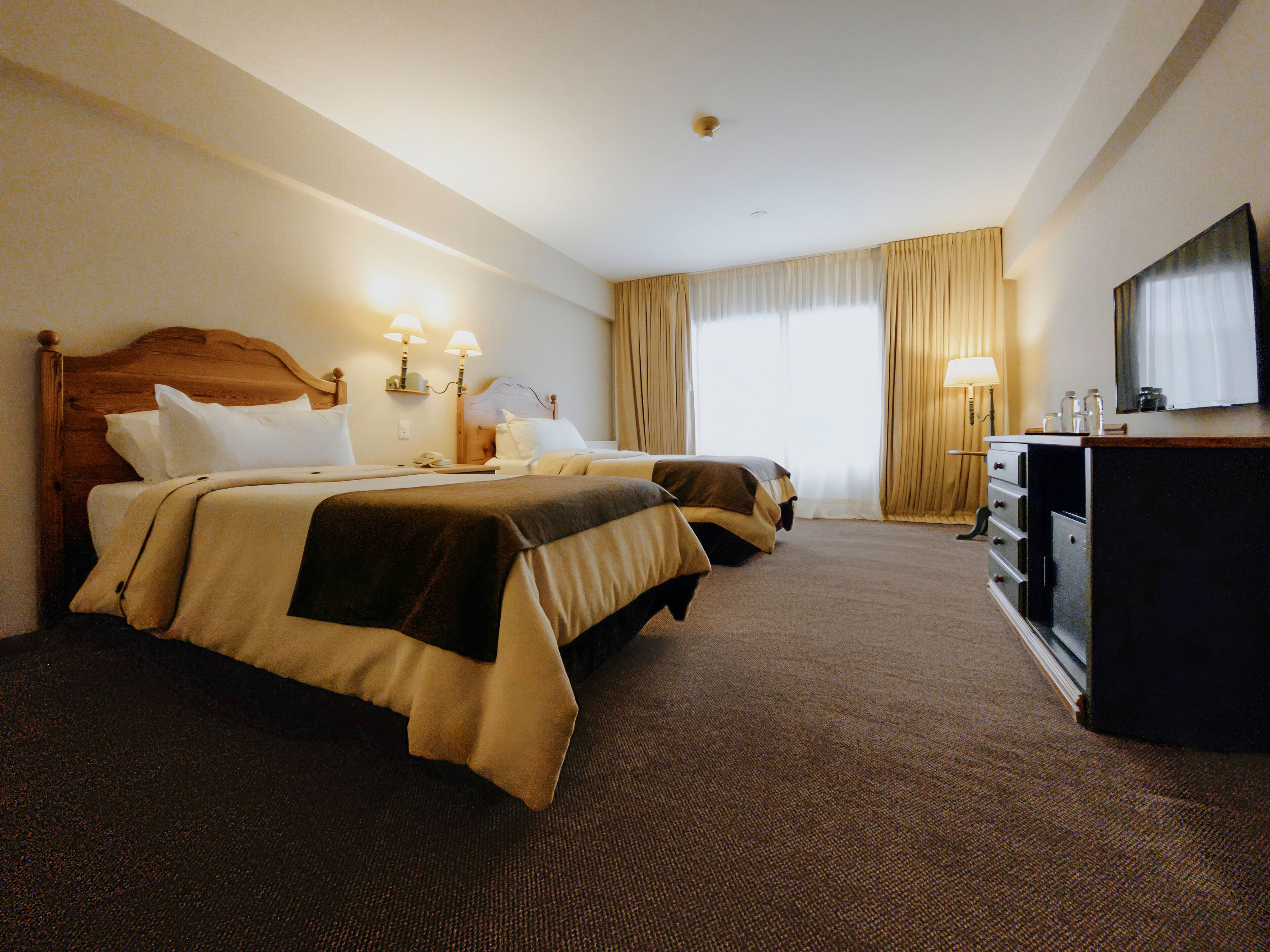 Une chambre d’hôtel avec deux lits, un bureau et une télévision.