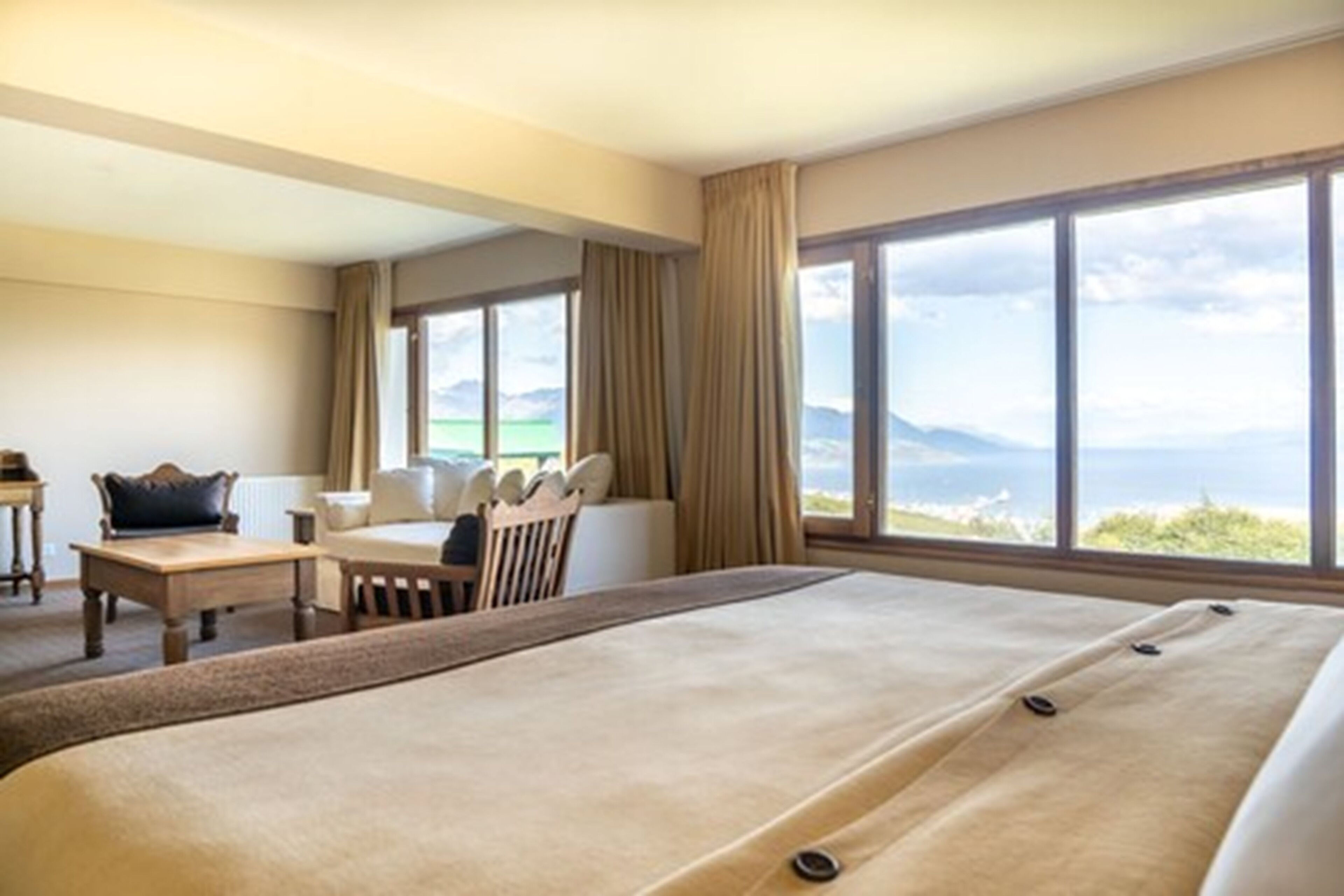 Habitación de hotel con dos camas, un escritorio y vista al mar.