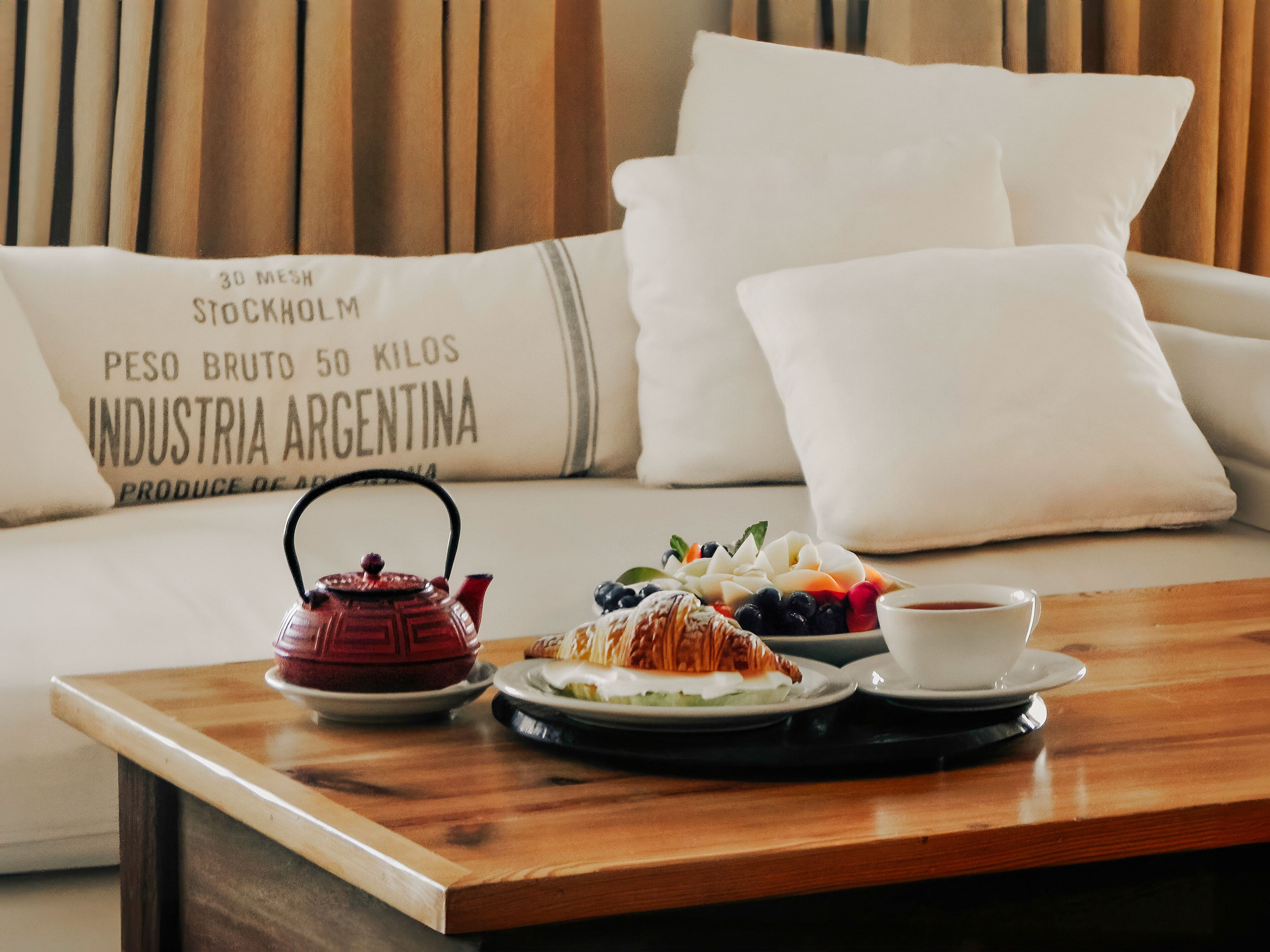 A dining table with a teapot, pastries, and a cup of coffee.