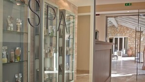 A spa reception area with a glass display case labeled "SPA" and a stone wall in the background. - Is Arenas Resort (Narbolia)