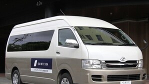Un fourgon blanc arborant le logo « QUINTESSA » est garé devant un immeuble.