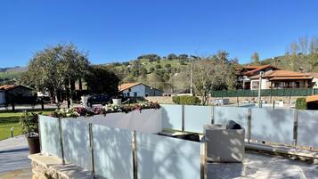 Um pátio com paredes de pedra, piscina e vista para casas e colinas ao redor.