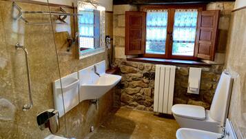 Un baño con bañera, dos lavabos, inodoro, ducha y ventana con cortinas.
