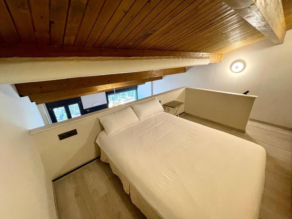 Un dormitorio con una cama, una ventana y una mesita de noche.