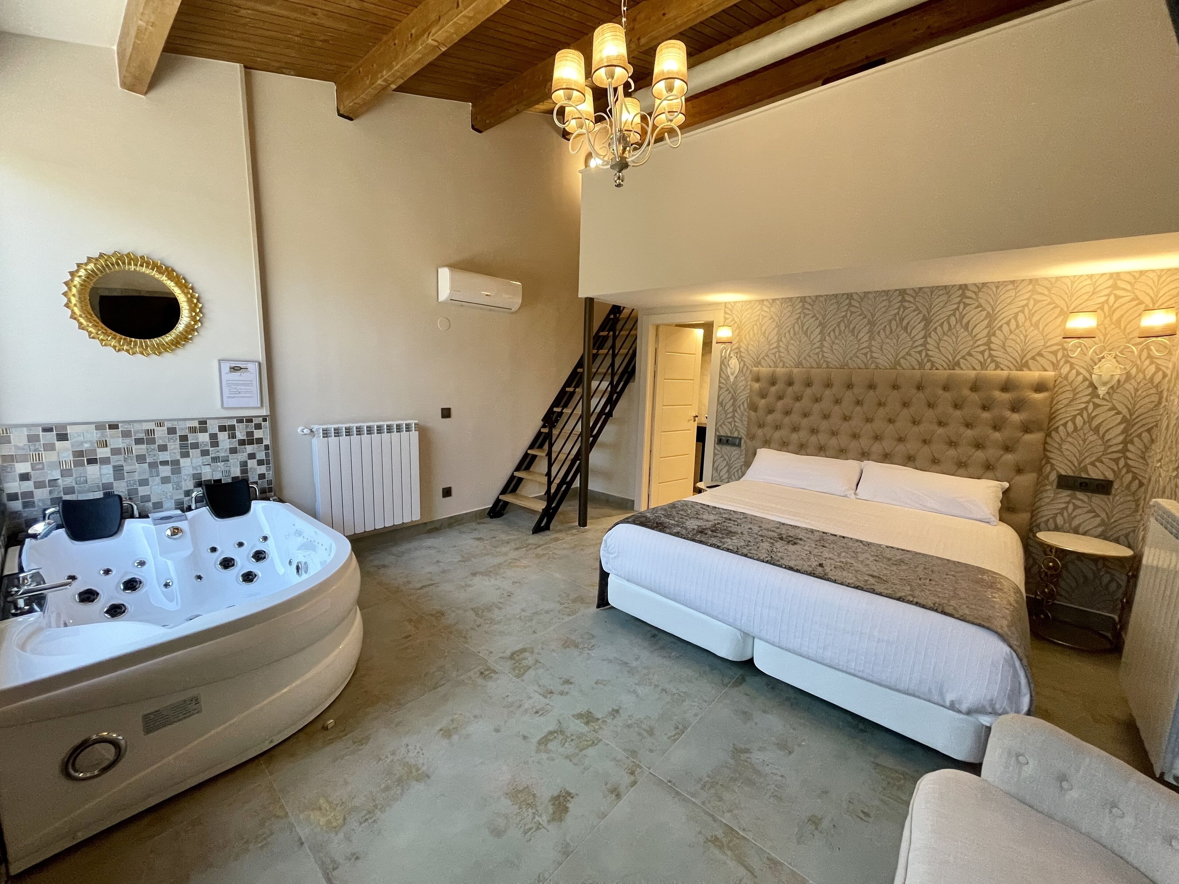 Une chambre dotée d’un grand lit, d’un coin salon, d’une salle de bain avec jacuzzi et d’un escalier.