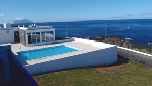 Un bâtiment moderne doté d’une piscine, d’une façade en verre et offrant une vue sur l’océan.