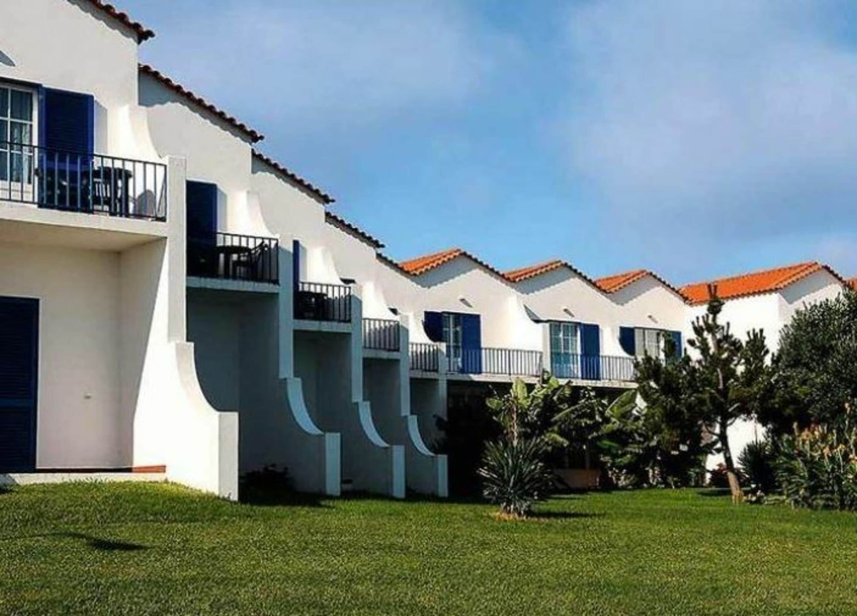 A row of white buildings with red-tiled roofs and balconies.