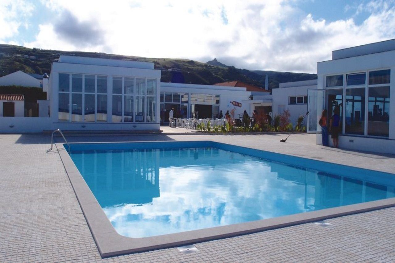 A swimming pool area with a clear blue pool, surrounded by modern buildings with large windows.
