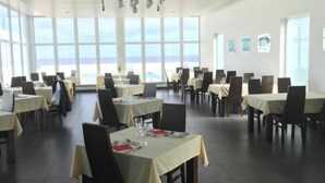 Un espace repas avec des tables dressées, de grandes fenêtres offrant une vue dégagée et un design moderne au plafond.