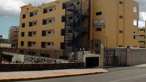 A multi-story building with a yellow facade, a visible staircase, and a gated entrance. - Apartamentos Amazonas (San Bartolomé de Tirajana)