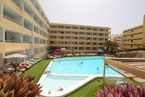 A hotel pool area with multiple levels of balconies, a swimming pool, and sun loungers. - Apartamentos Amazonas (San Bartolomé de Tirajana)