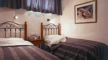 Quarto com duas camas de solteiro, mesa de cabeceira, luminária na parede e um quadro emoldurado.