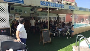 An outdoor restaurant with a grill and a sign advertising 'Bavaria Holland's Premium Beer'. - Apartamentos Amazonas (San Bartolomé de Tirajana)