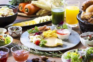 A variety of breakfast foods including eggs, toast, and pastries, along with drinks and salads.