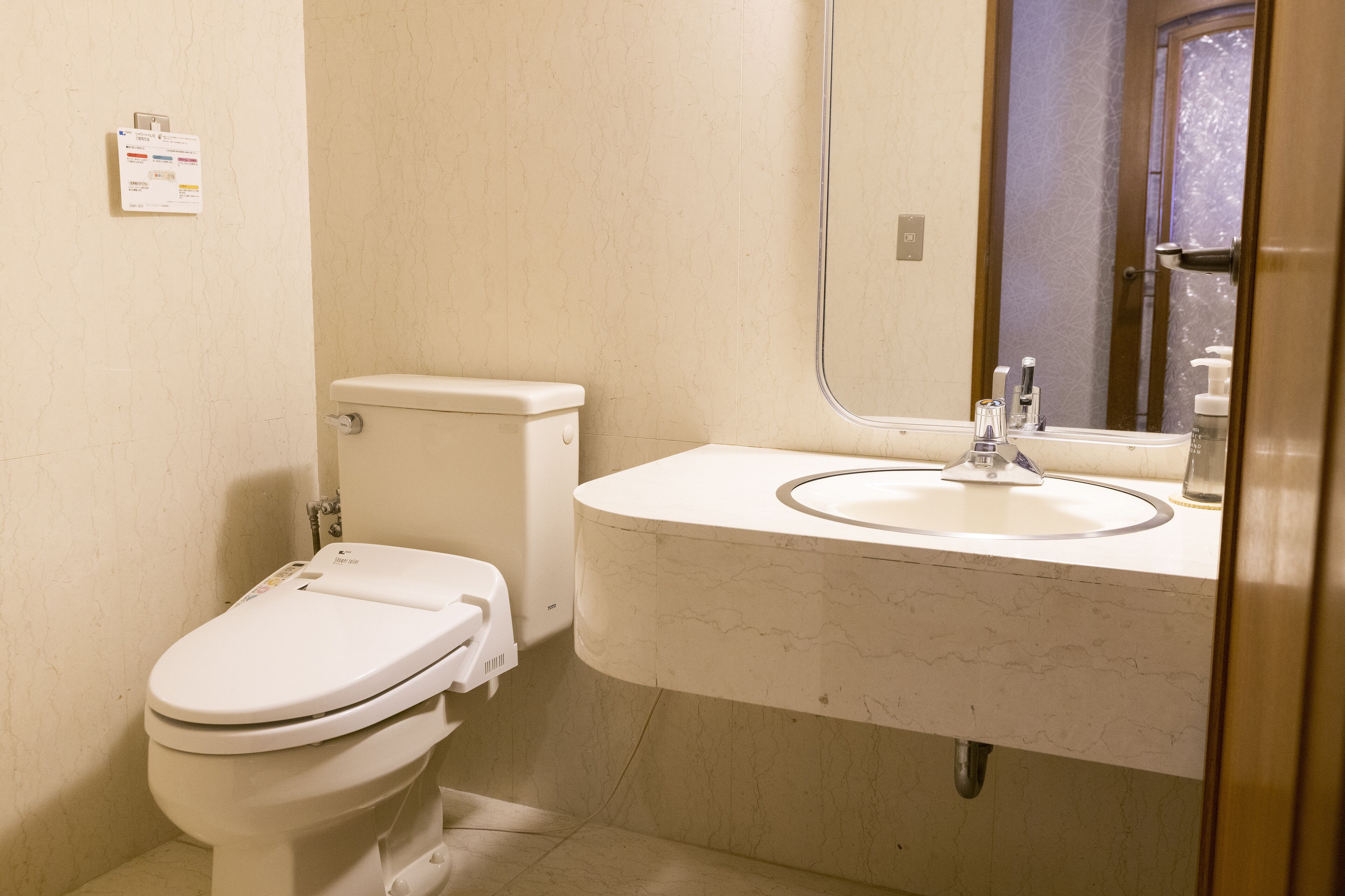 A bathroom with a toilet, sink, and mirror.