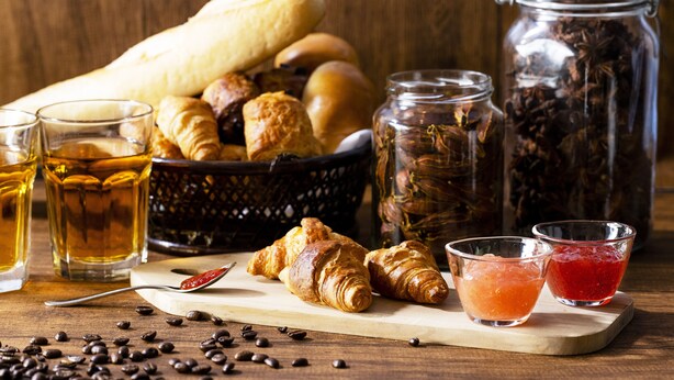 Een houten tafel met gebak, koffiebonen en twee theeglazen.