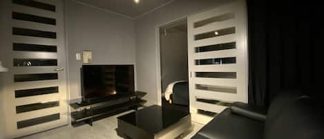 A modern living room with a flat-screen TV, a sofa, and a coffee table.