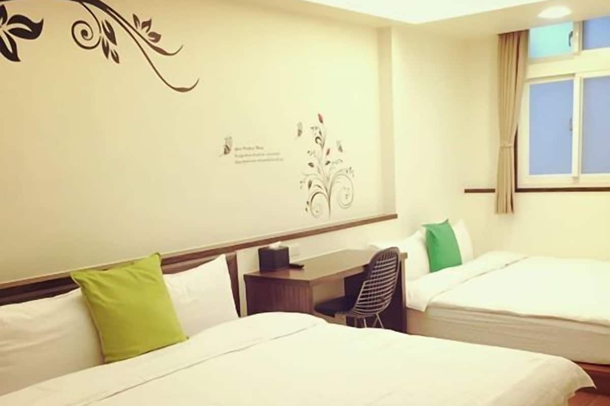A hotel room with two beds, a desk, and a chair.