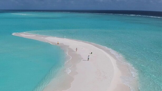 Una playa con aguas turquesas cristalinas y una orilla arenosa.