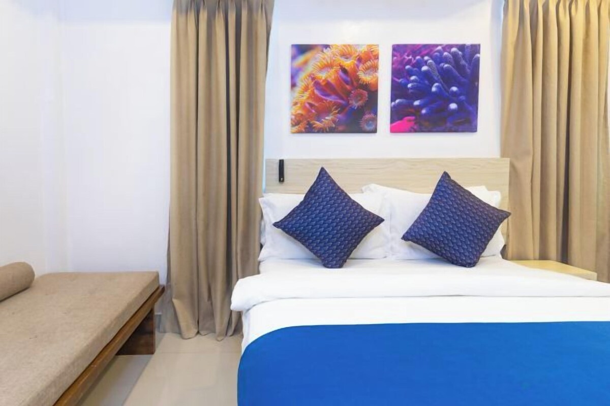A hotel room with a bed, two pillows, a headboard, and two wall art pieces.