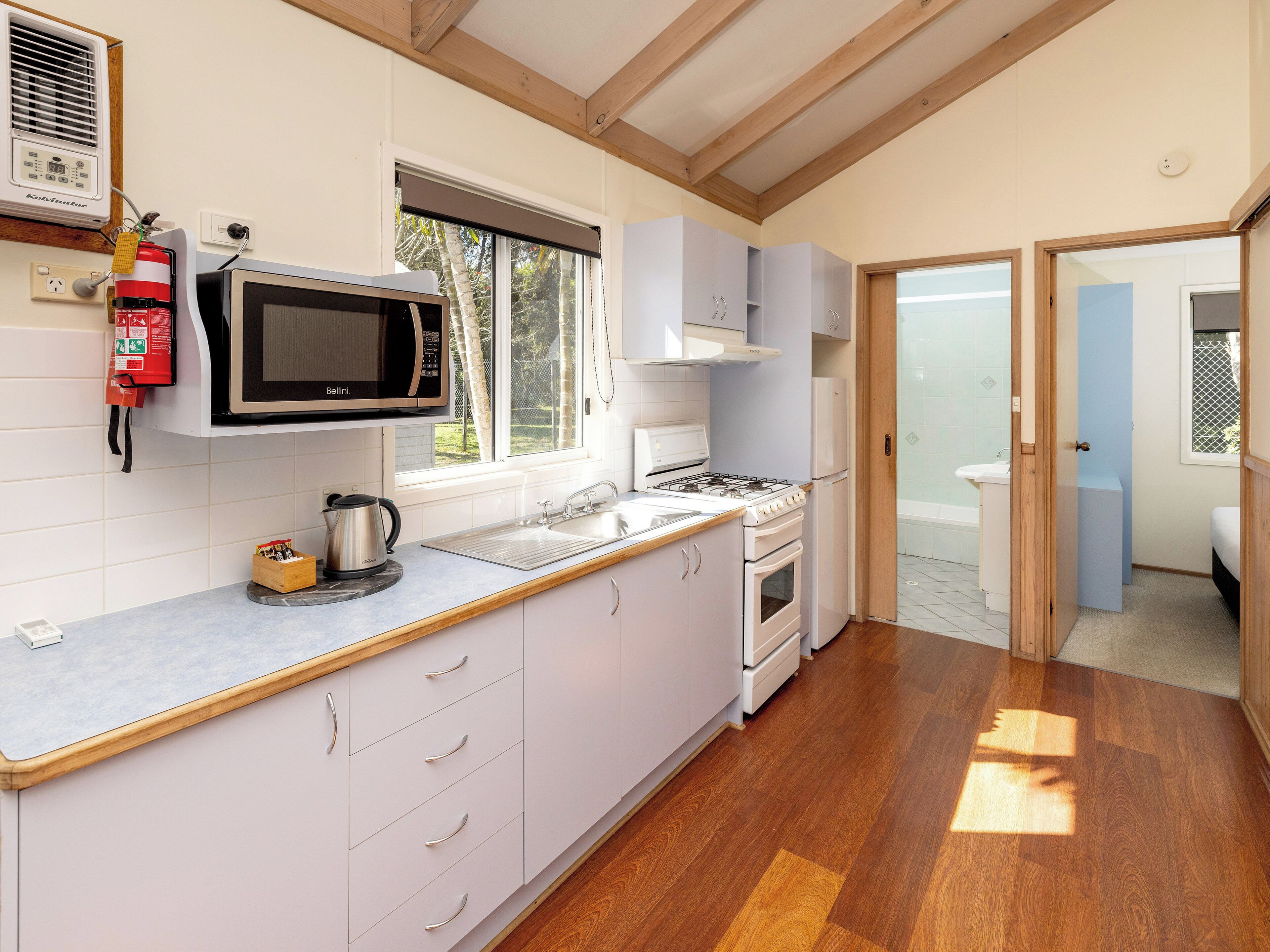 A modern kitchen with white cabinets, a microwave, a gas stove, and a sink.